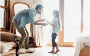 Vater tanzt mit Kind in Zimmer, Wohlfühlatmosphäre
