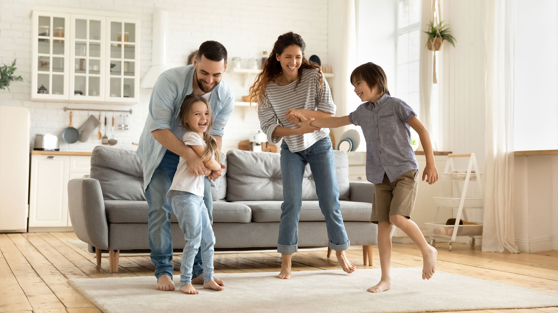 Familie mit 2 Kindern tanzt gemeinsam im Wohnzimmer