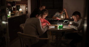 Familie sitzt bei Kerzen bei Tisch.