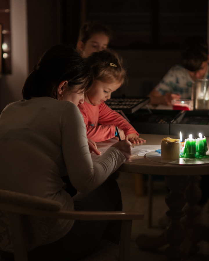 Familie sitzt bei Kerzen bei Tisch.